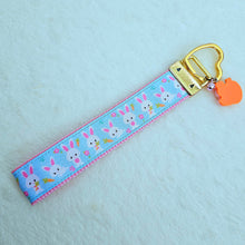 Load image into Gallery viewer, Bunnies with Carrots & Flowers on Light Blue Yellow Gold Key Chain Fob with Enameled Bunny Charm